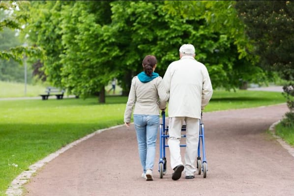 A caregiver assisting a resident on a pathway