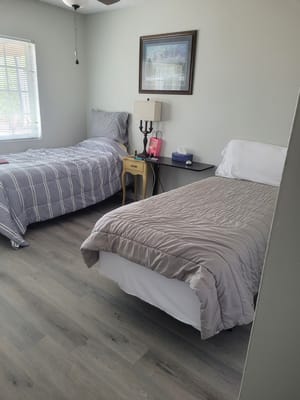 A shared bedroom with two beds, bedside tables, and a window.