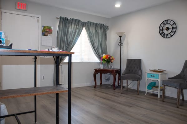 A well-lit common area with a table, chairs, and floral arrangement.