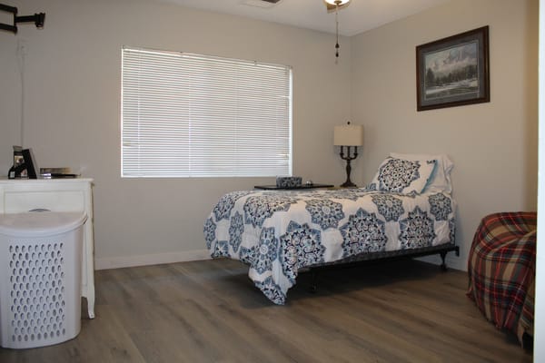 A well-furnished bedroom with a bed, lamp, and window.