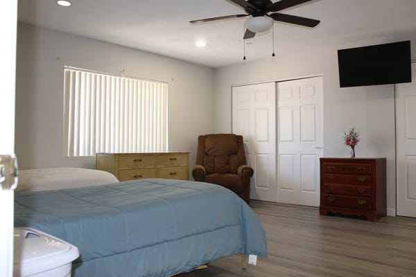 Bedroom with a blue quilt, dresser, and reclining chair