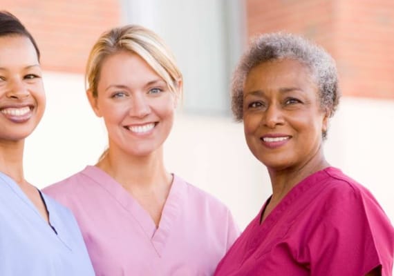Three smiling healthcare staff members in scrubs
