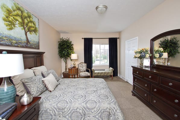 A well-decorated bedroom with a bed, dresser, and armchair.