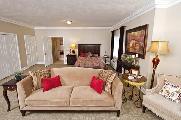 Stylish living room with a bed in the background at CrownPointe of Carmel