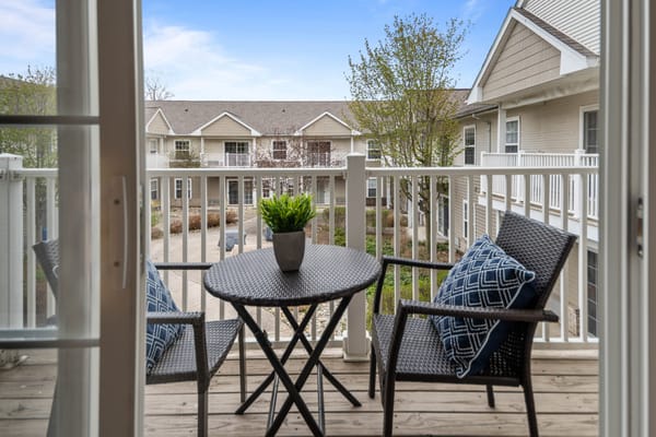 Cozy balcony with chairs and a small table overlooking the courtyard.