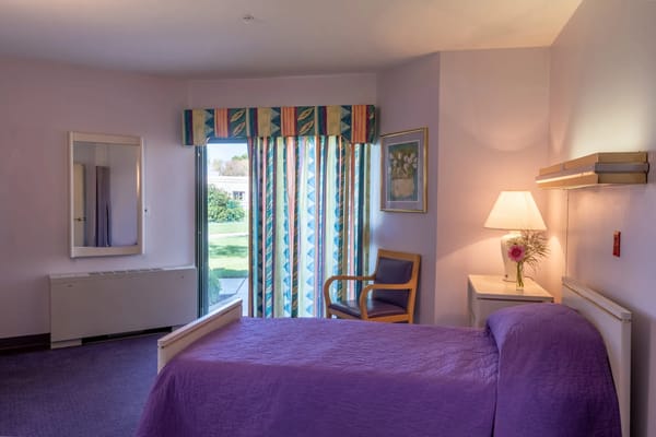 Cozy resident room with bed, chair, and curtains