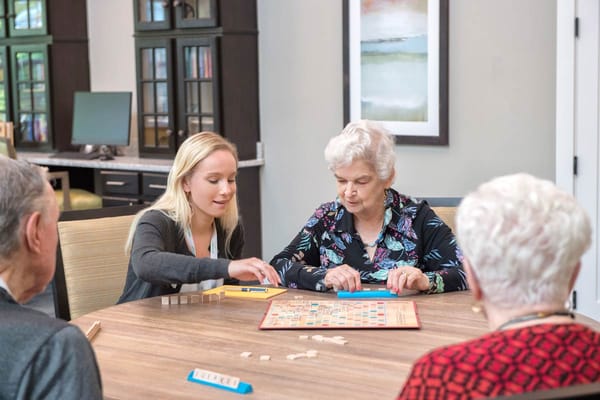 Residents and staff playing Scrabble in a cozy room
