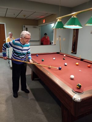 Senior resident playing pool at a game table