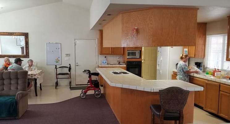 Common area with residents engaged in activities and staff preparing food