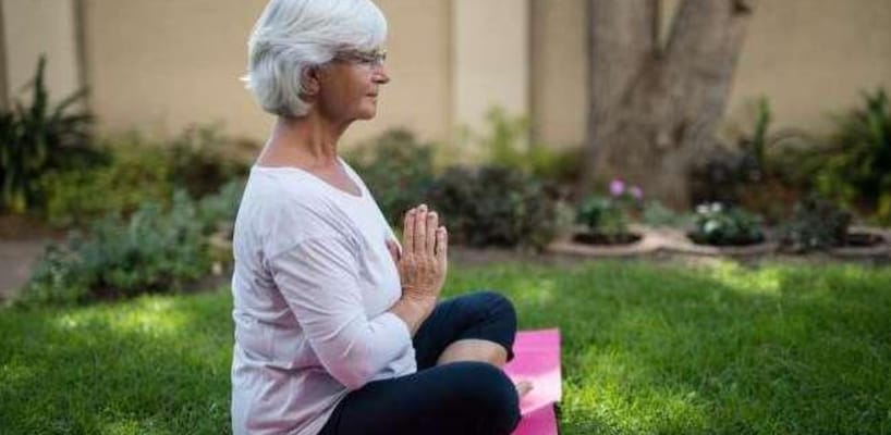 Senior woman practicing yoga in a garden