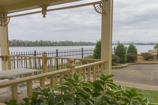 View from the patio overlooking the river with a fence and greenery