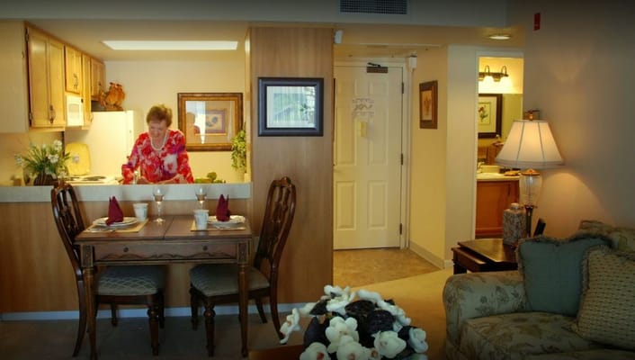 Woman preparing food in a cozy kitchen with a dining area