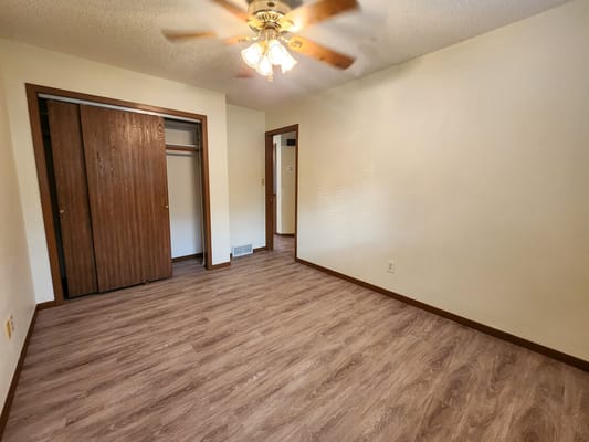 Spacious living area with wooden floors and ceiling fan