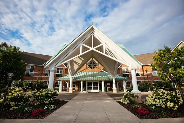 Main entrance of Glacier Hills with a covered awning and flowering shrubs