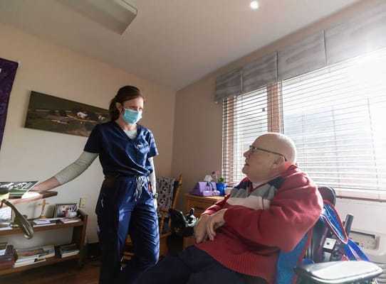 A staff member assisting a resident in their room