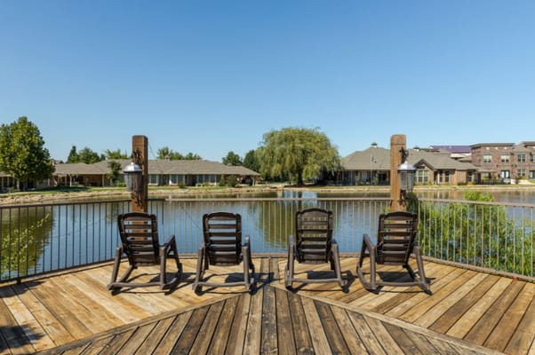 Rocking chairs on a deck overlooking a serene lake