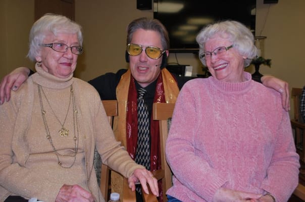 Two smiling residents and a staff member in a common area