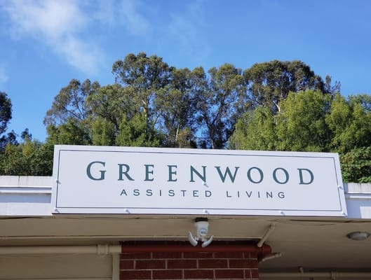 Greenwood Assisted Living exterior sign against trees