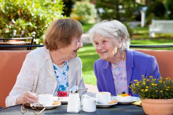 Two smiling residents enjoying dessert outdoors