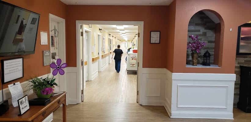 A corridor in a senior care facility with a staff member and decor