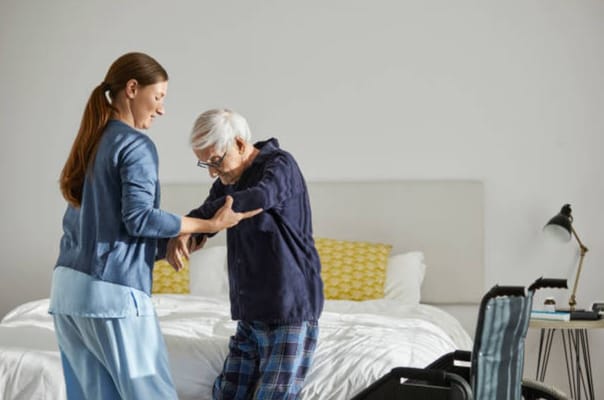 Caregiver helping an elderly person in a bedroom