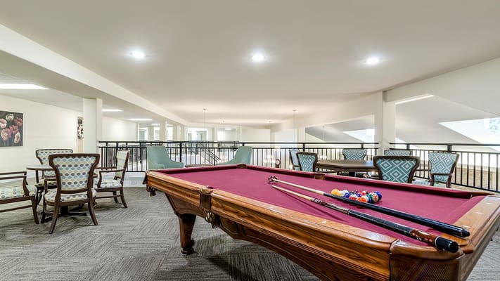 Interior view of the billiards room with a pool table and seating area.