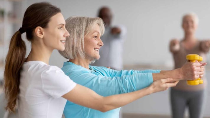 Resident exercising with staff assistance in a fitness area
