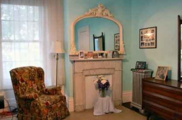 Living room with floral chair, fireplace, and decorative mirror