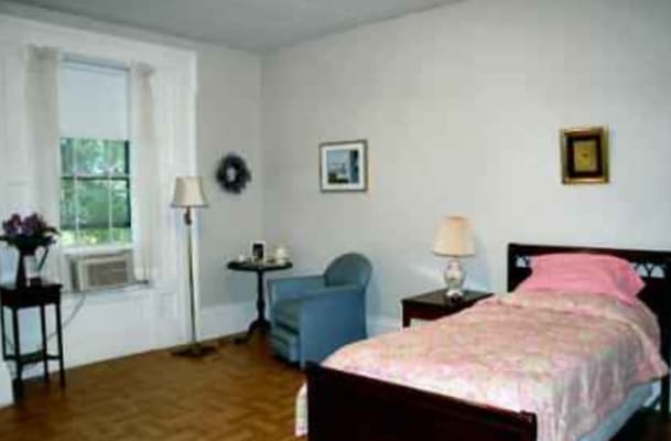 A cozy bedroom with a bed, chair, and lamp.