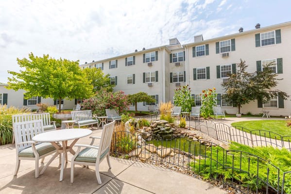 Scenic garden area with seating and a pond at Independence Village Fishers South.
