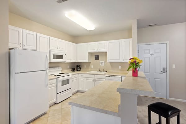 Well-equipped kitchen with white cabinets and appliances