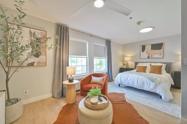 Well-decorated bedroom with a bed, armchair, and natural light