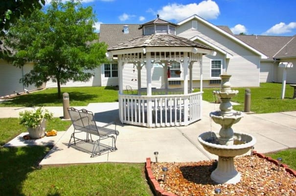 A gazebo surrounded by landscaped lawn and a fountain