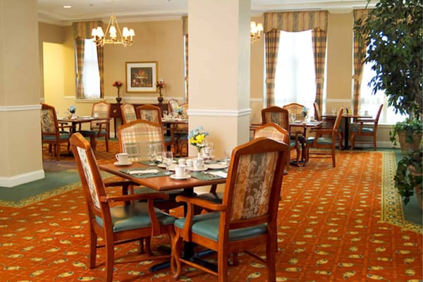 Cozy dining area with wooden tables and chairs at Neville Place Assisted Living.