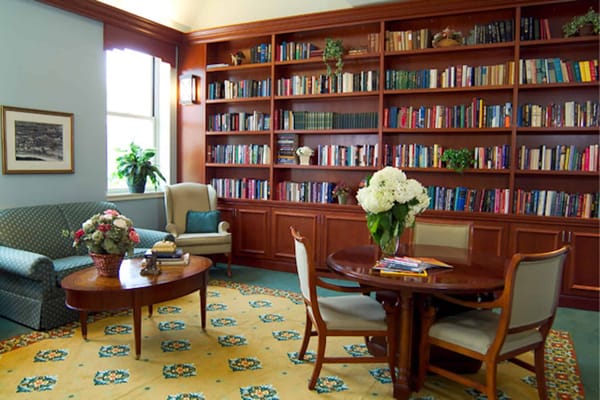 A cozy library with bookshelves, a seating area, and a round table.