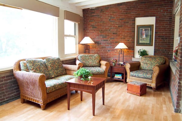 A comfortable lounge with floral sofas, a wooden table, and warm lighting.