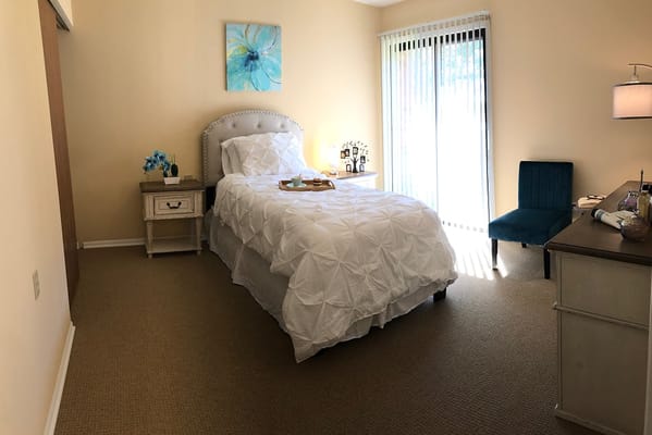 Brightly lit private resident room with bed and decor