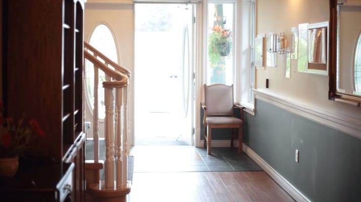 Bright foyer with a staircase and a chair in One Willow Manor.