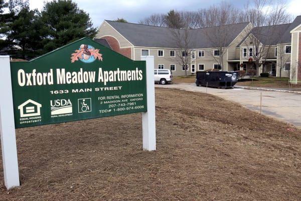 Sign for Oxford Meadow Apartments showing address and contact information.