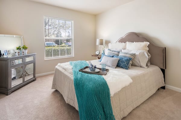 A tastefully decorated bedroom with a bed, decorative pillows, and a neatly arranged nightstand.