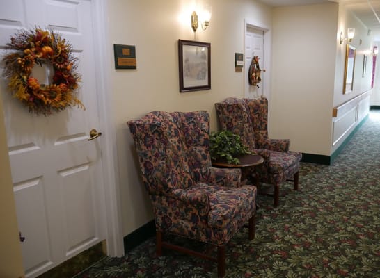 Two floral armchairs and a small table in a hallway