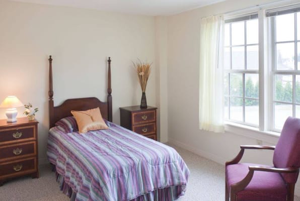 A cozy bedroom with a single bed, two nightstands, and a chair.