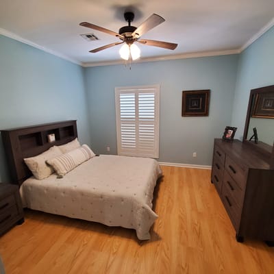 A well-furnished bedroom with a bed, dresser, and window shutters.