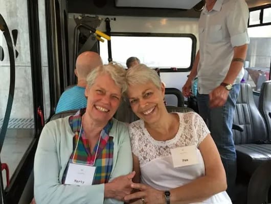 Two women smiling together on a bus