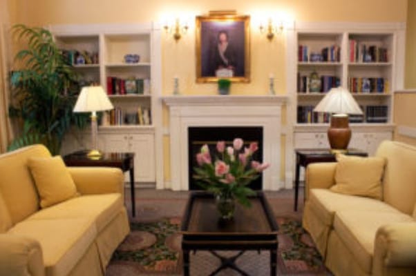 A warm living room featuring yellow sofas, a fireplace, and bookshelves