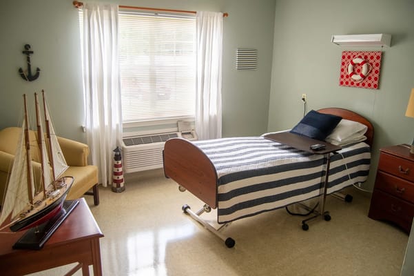 Private room with a bed, chair, and nautical decor.