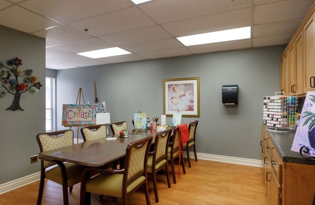 A spacious art room with a long table and art supplies.