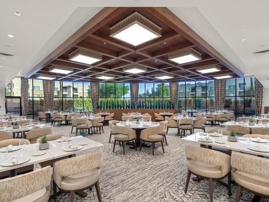 Dining area with tables and chairs, large windows for natural light