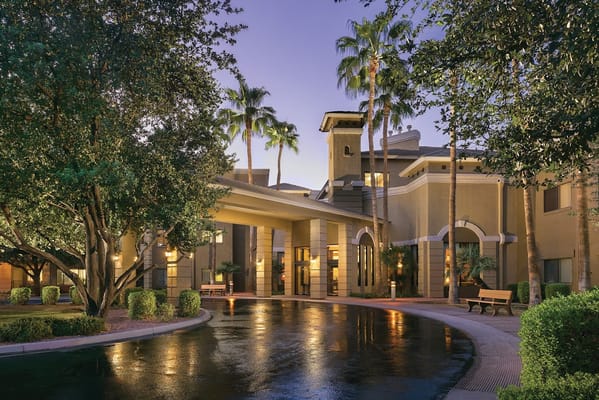 View of the entrance to Robson Reserve at Sun Lakes with palm trees and wet pavement at dusk.