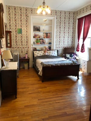 Private resident room with floral wallpaper and wooden furniture